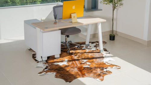 Home office setup with a Tricolor Cowhide Rug under a modern desk and chair.