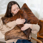 Woman hugging a large brindle cowhide pillow indoors