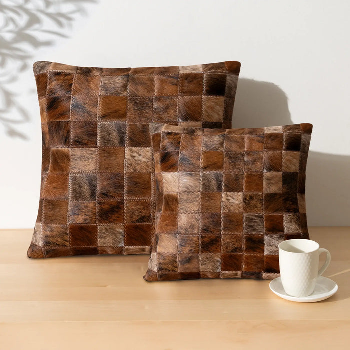 Two brown checkered pillows on a wooden surface with a white cup and saucer.