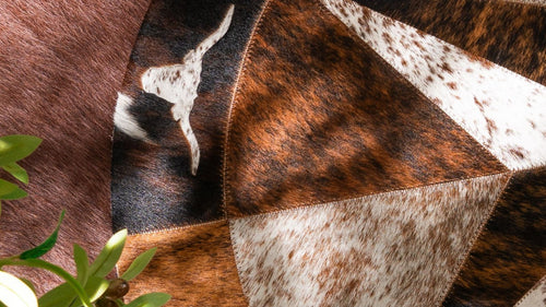 Close-up of a round cowhide rug, showing a natural Texas Longhorn silhouette inlay.