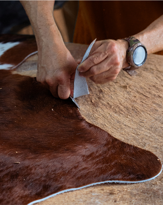 Person working with leather on a cowhide rug