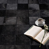 Close-up of Rhodes black patchwork cowhide rug, hand-sewn square seams