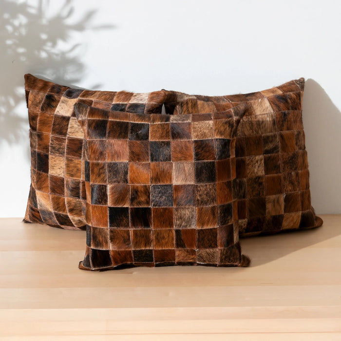 Patchwork pillow with brown and black squares on a wooden surface