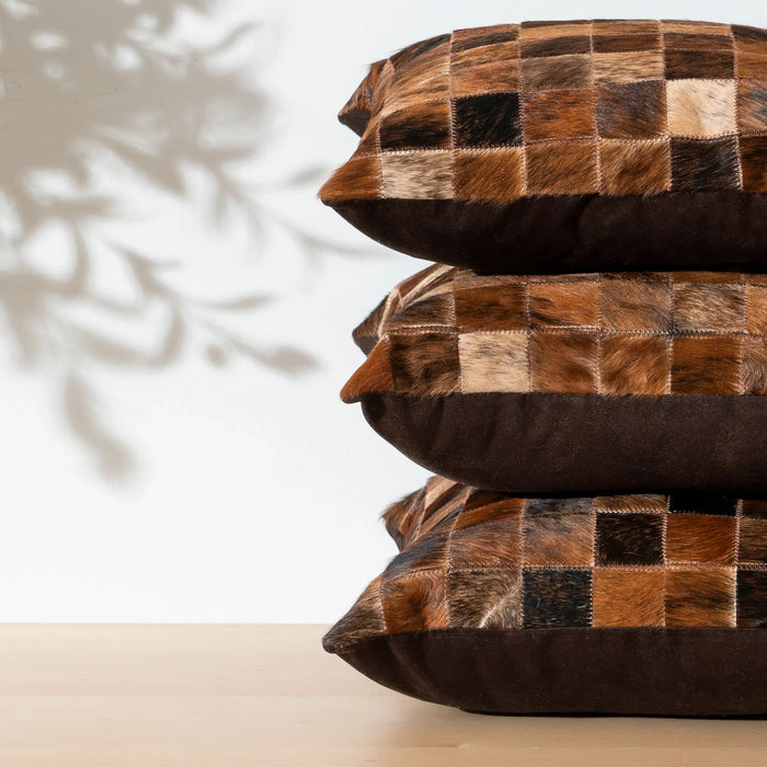 Stack of brown patchwork pillows on a neutral background
