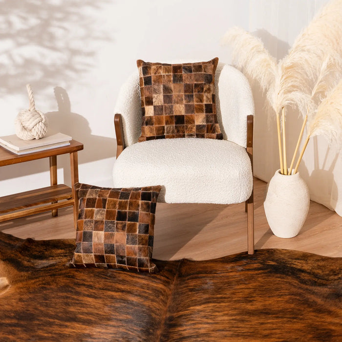 White armchair with checkered brown pillow in a room with a wooden side table and decorative items.