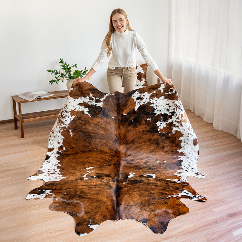 Woman holding a cowhide rug in a room with a wooden floor and white walls.