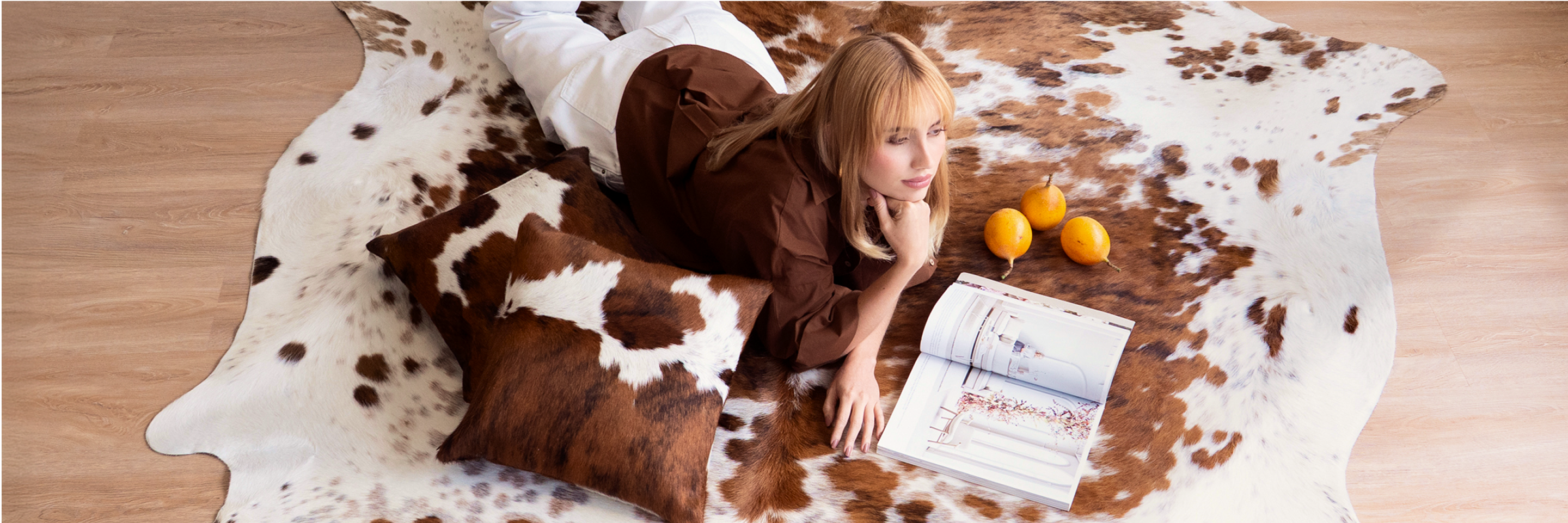 Woman lying on a cowhide rug with a newspaper and oranges