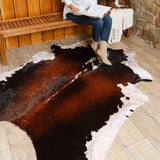 Chocolate and white cowhide rug draped over a sofa as an accent throw