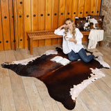 Chocolate and white cowhide rug laid flat on a hardwood floor, showing asymmetric pattern